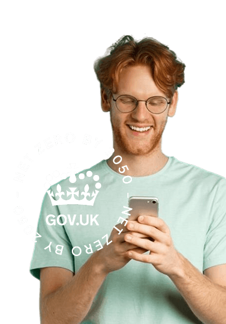 A man smiling while looking down at his phone with the Gov UK Net Zero badge to the left