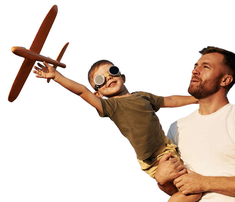 A child playing with a wooden toy aeroplane with a father holding him looking upwards